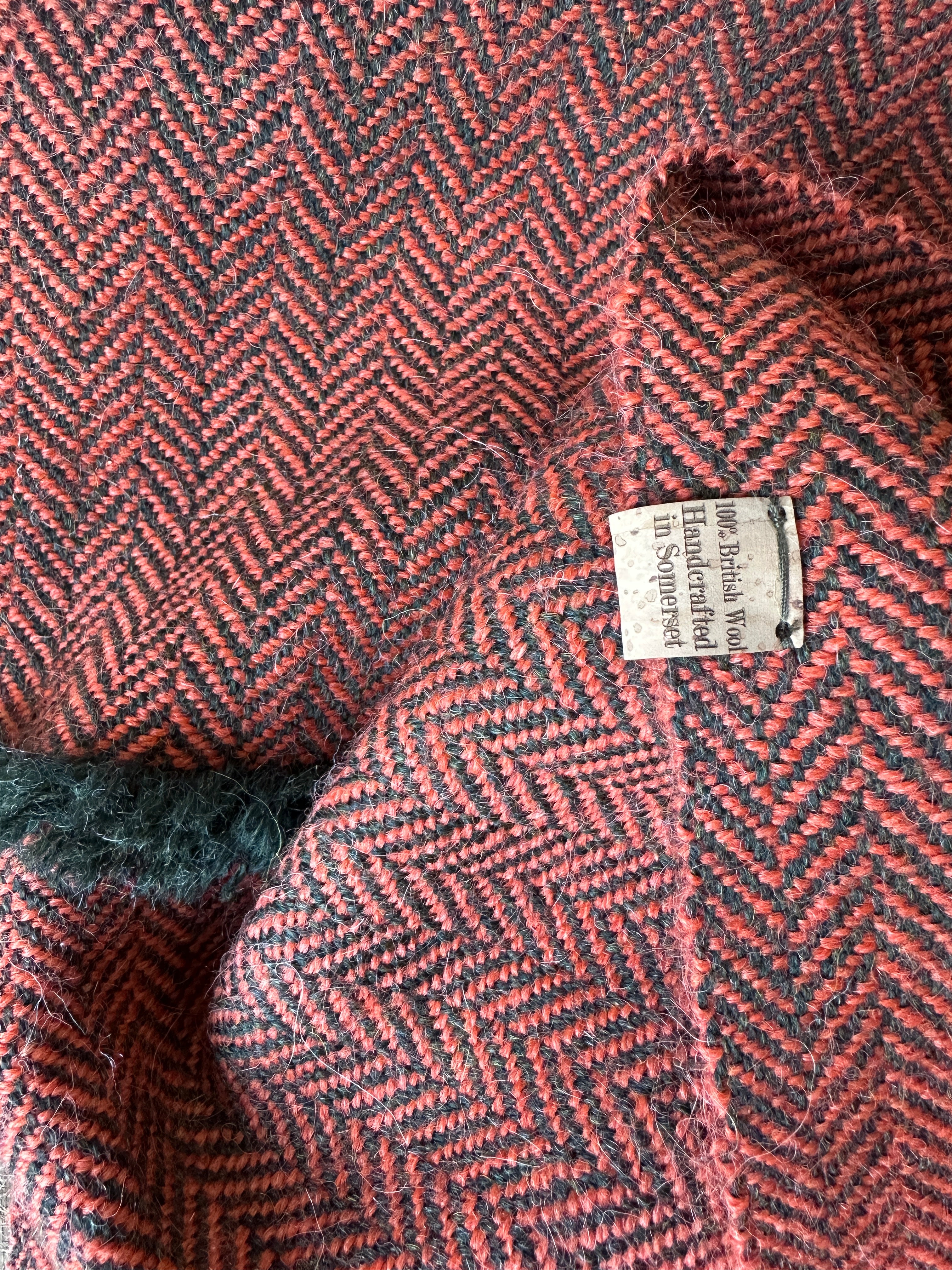 Close-up of a herringbone-patterned fabric with a label saying 100% British wool, handcrafted in Somerset
