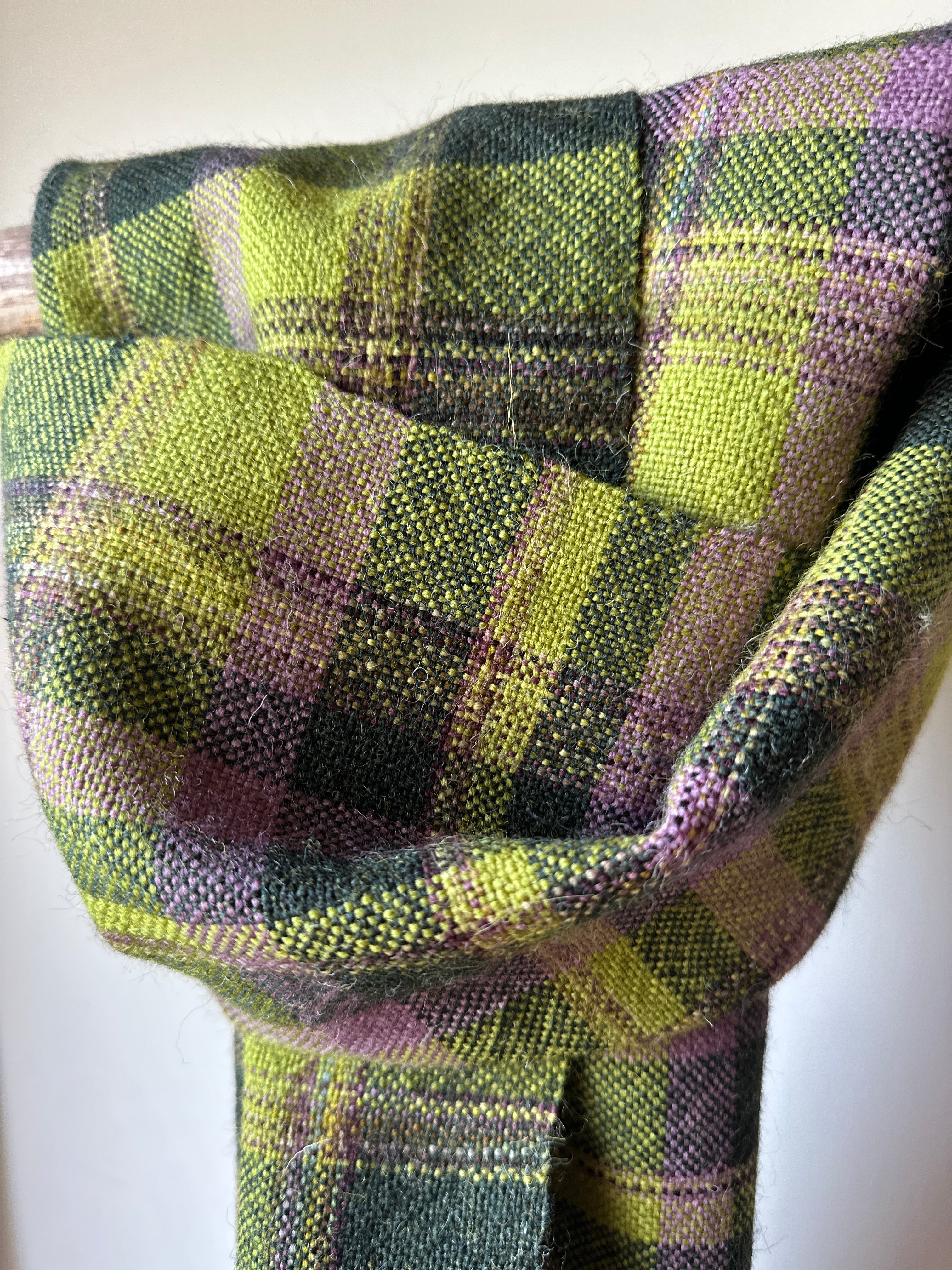 Close-up of a plaid fabric with green, and purple colours.